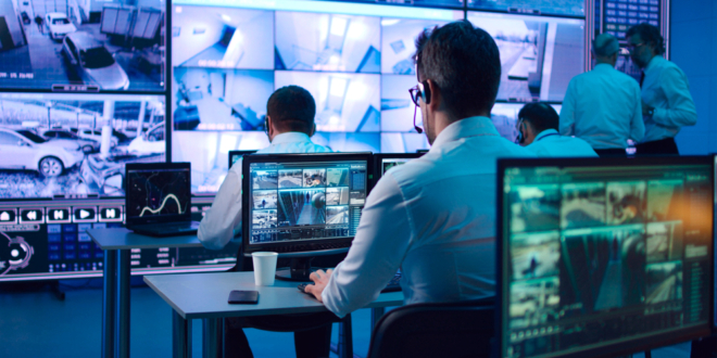 Pult centralizovanej ochrany s monitormi a pracovníkmi dohliadajúcimi na bezpečnosť objektov.