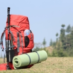 Turistický batoh s výbavou položený na skale s výhľadom na horskú krajinu